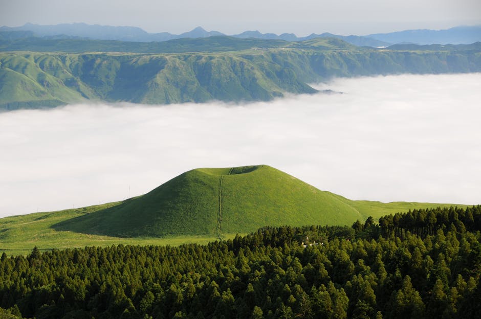 Stunning view of a green hill amidst rolling clouds in Aso, Japan.