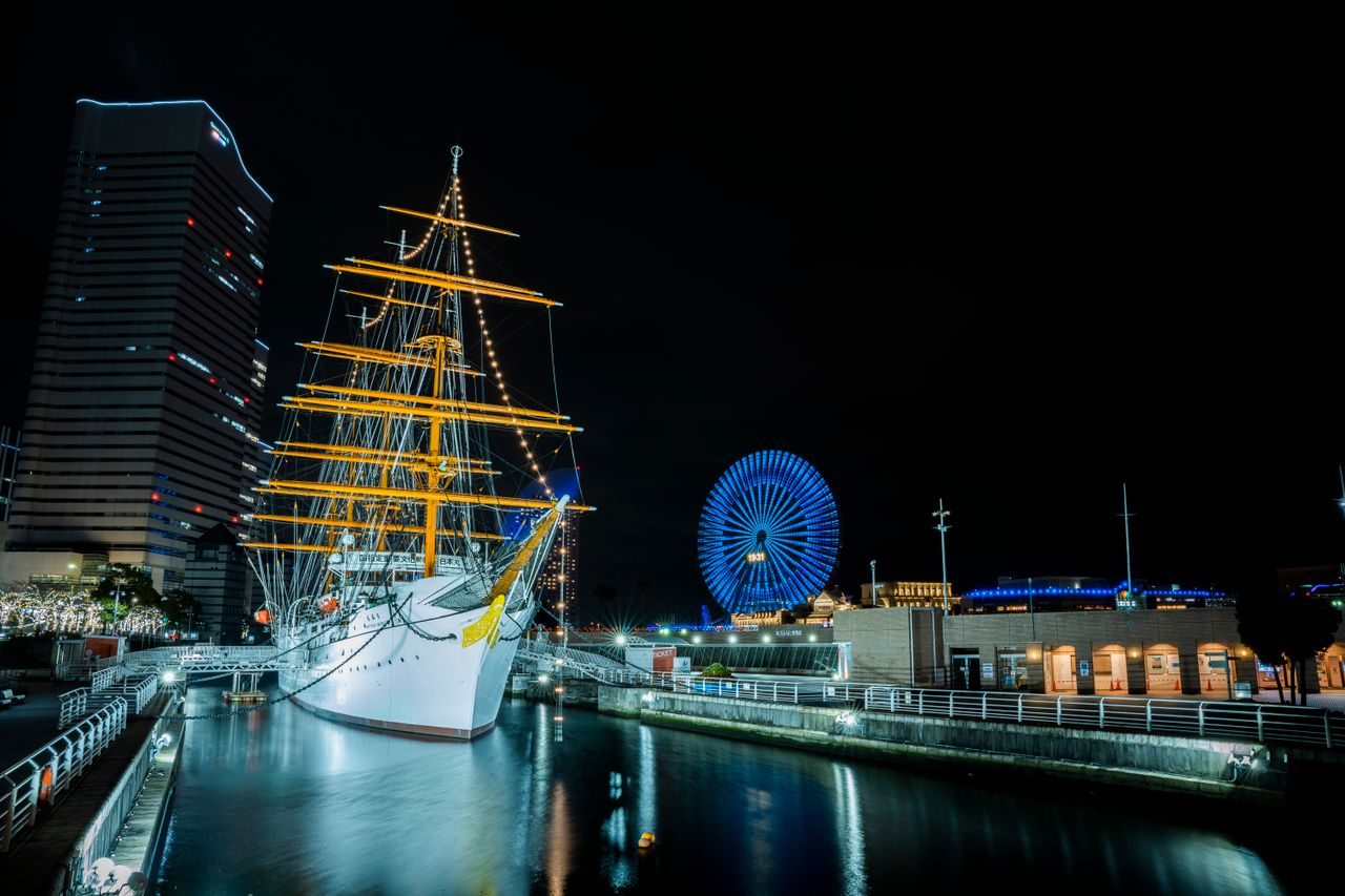 Stunning night view of Yokohama Harbor featuring the illuminated Ferris wheel and historic ship Nippon Maru.