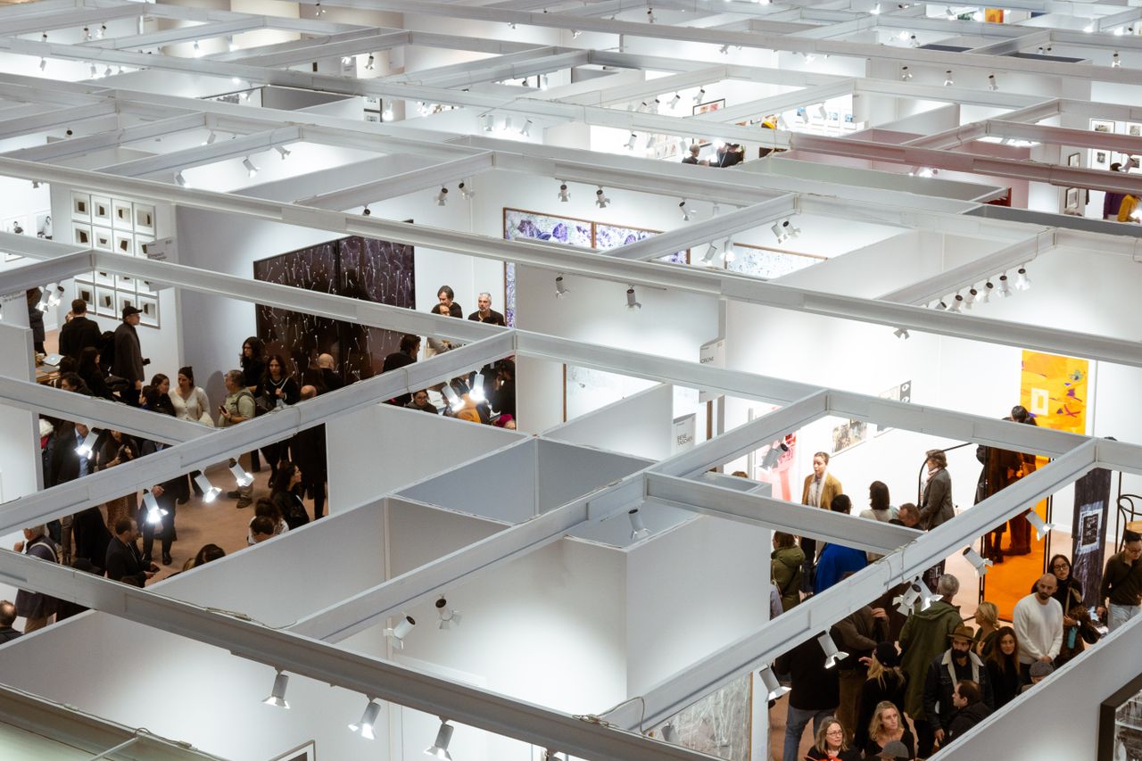 Aerial view of a crowded art exhibition in Paris with visitors in indoor galleries.