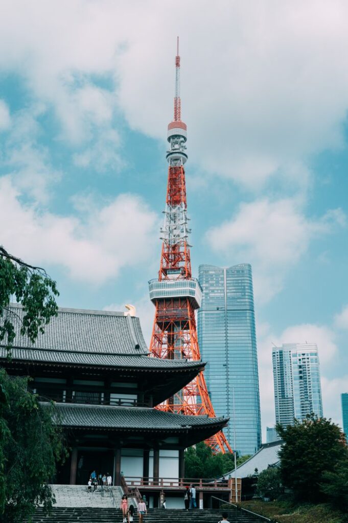 Tokyo Tower and Zojoji Temple under a blue sky, blending modern and traditional architecture.