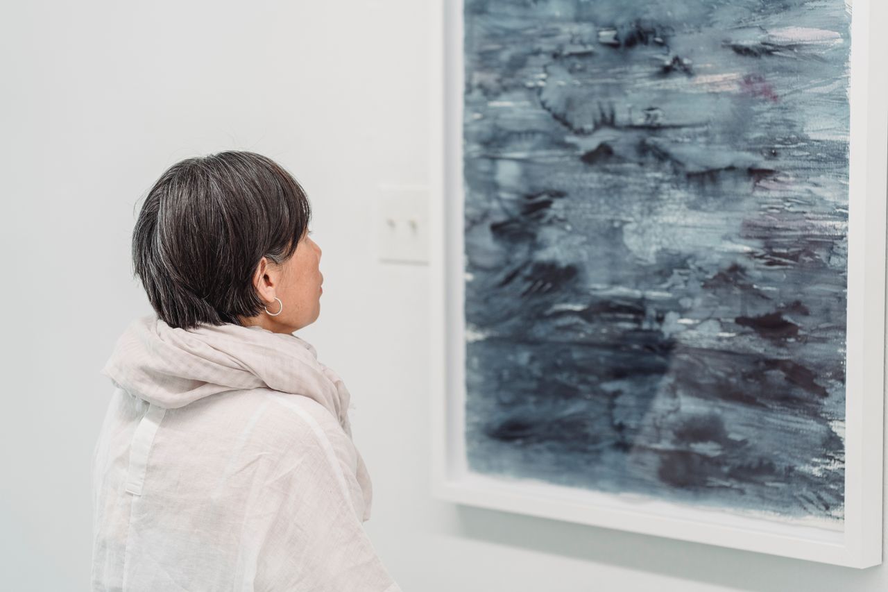 A woman looking at an abstract painting in a modern art gallery.