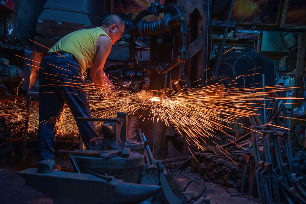 A blacksmith at work creating sparks in a vibrant workshop environment.